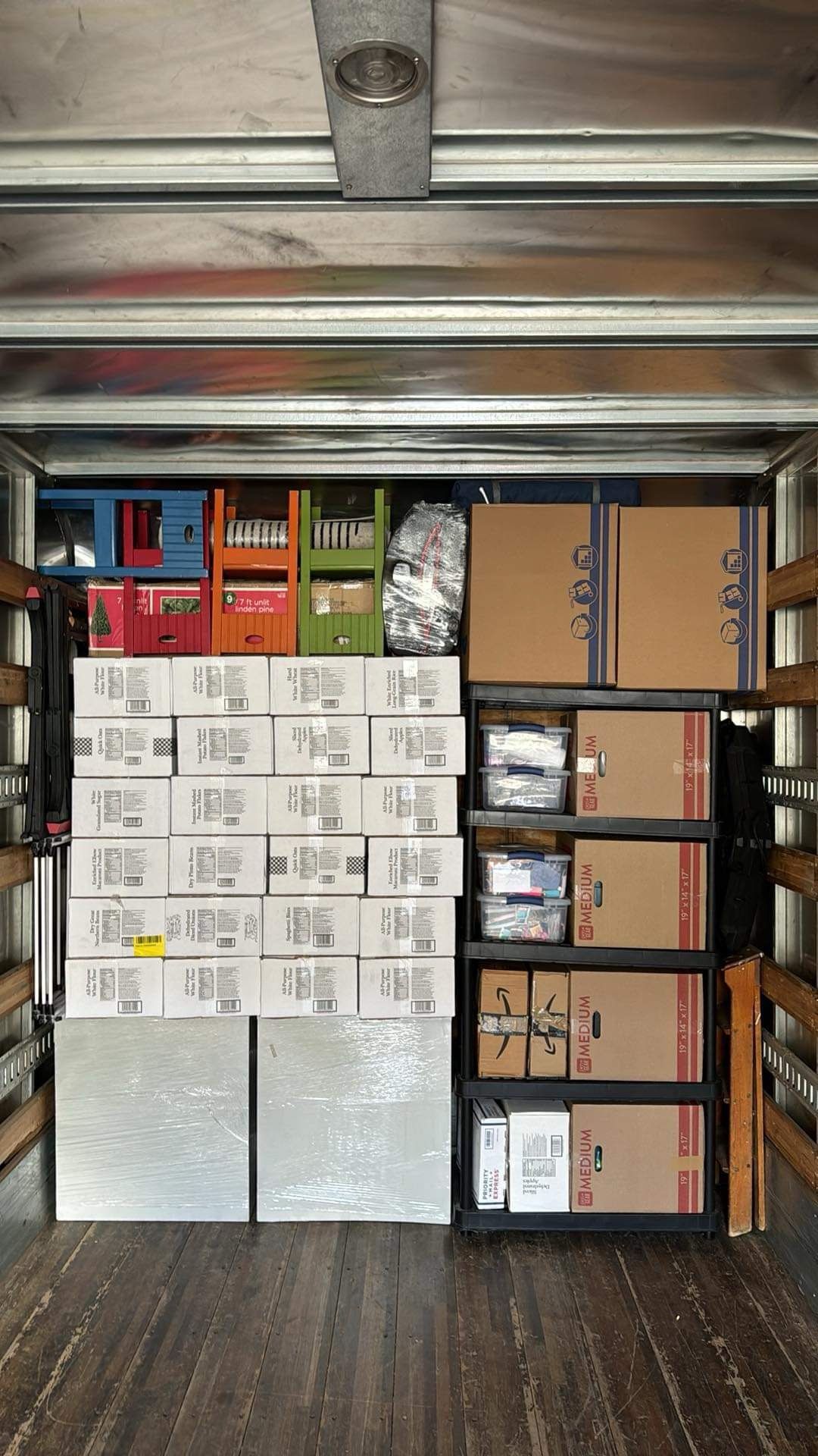 Storage unit packed with stacked cardboard boxes and bins on shelves, front view