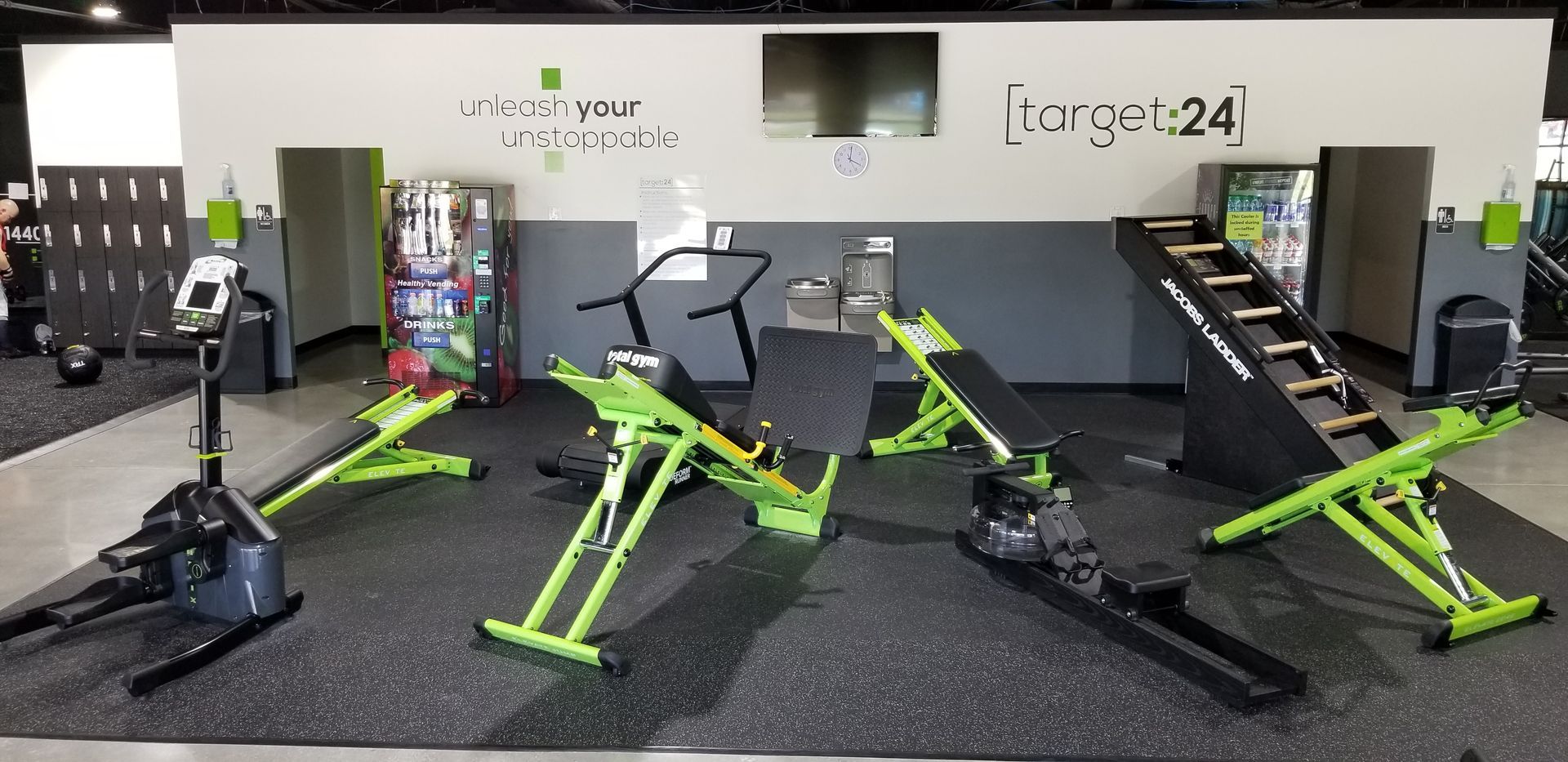 A gym with a lot of green exercise equipment on the floor.