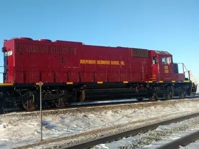 Red freight locomotive on tracks in a snowy yard under a clear blue sky