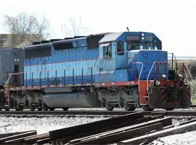 Blue and black diesel locomotive on railroad tracks in a rail yard