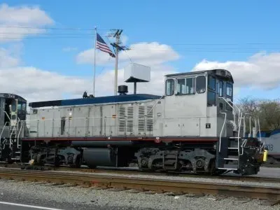 White locomotive on tracks with an American flag flying against a blue sky.