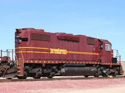 Red locomotive on tracks under a clear blue sky