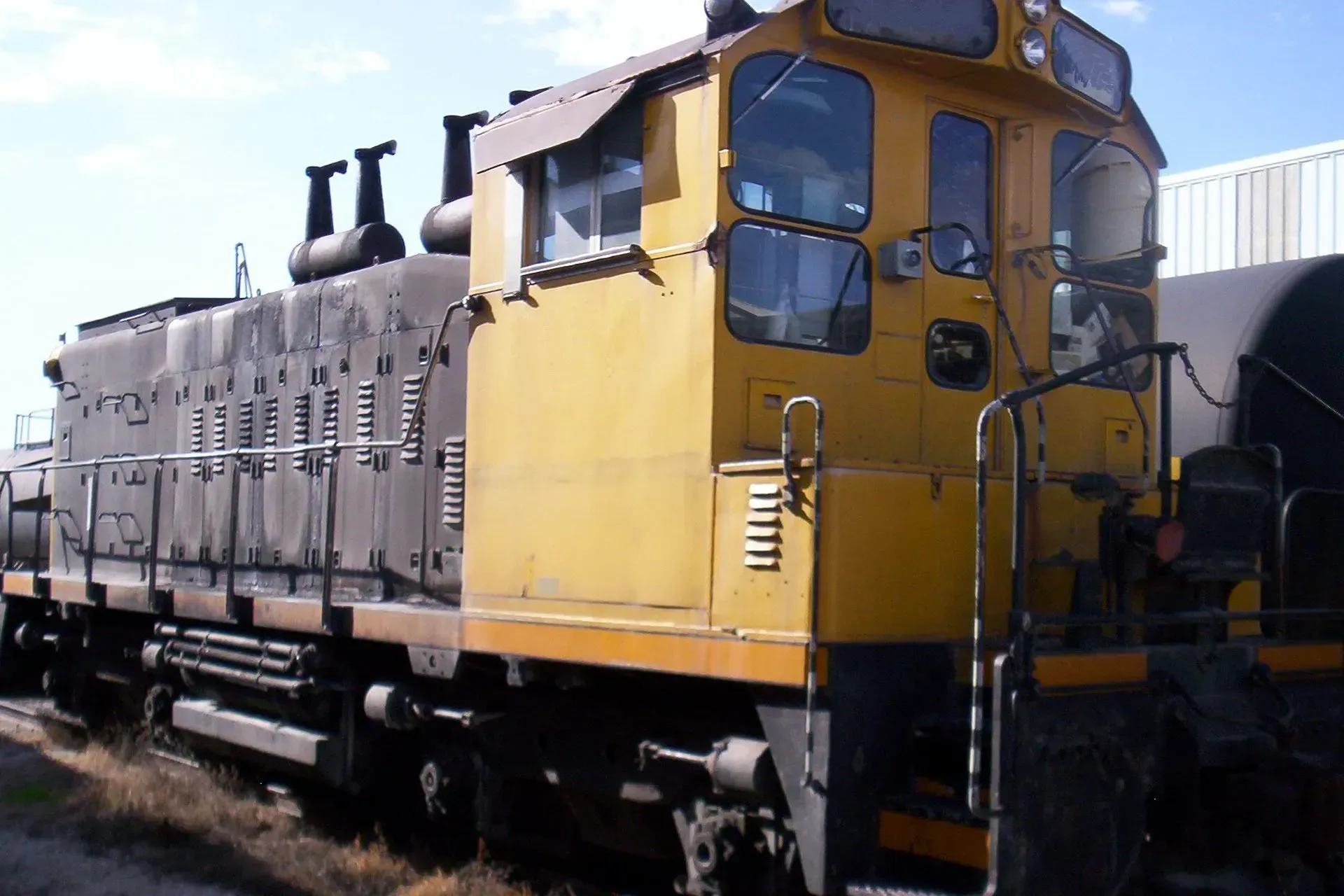 Yellow locomotive parked beside freight cars in a rail yard