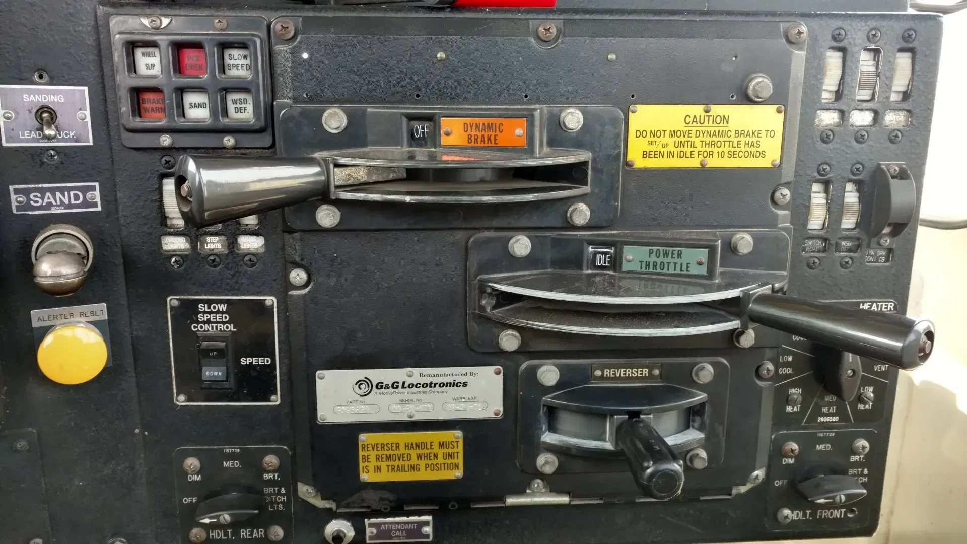 Close-up of a black control panel with knobs, switches, gauges, and warning labels on industrial equipment