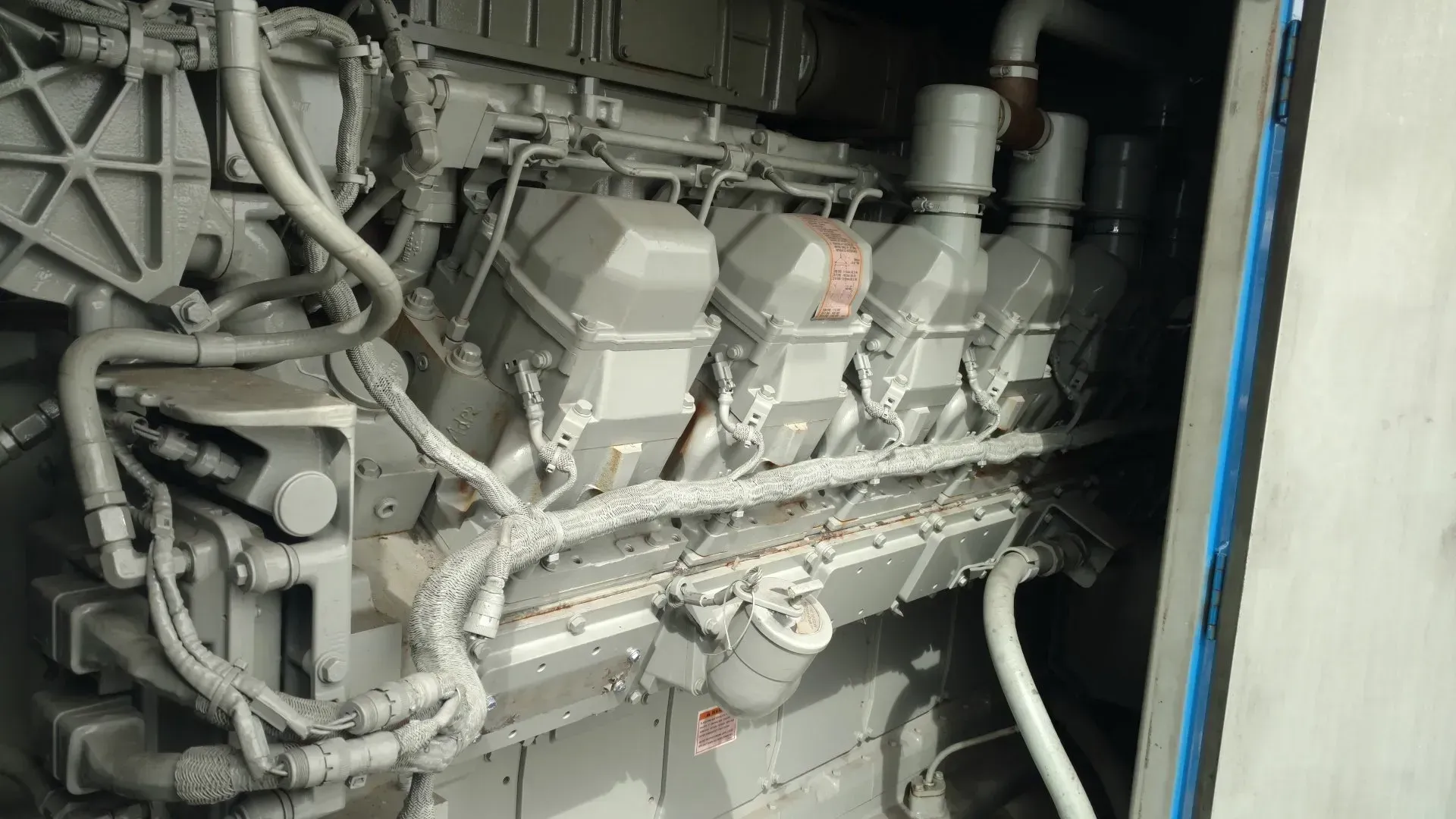 Industrial engine or generator machinery with tangled hoses and pipes in a cramped compartment