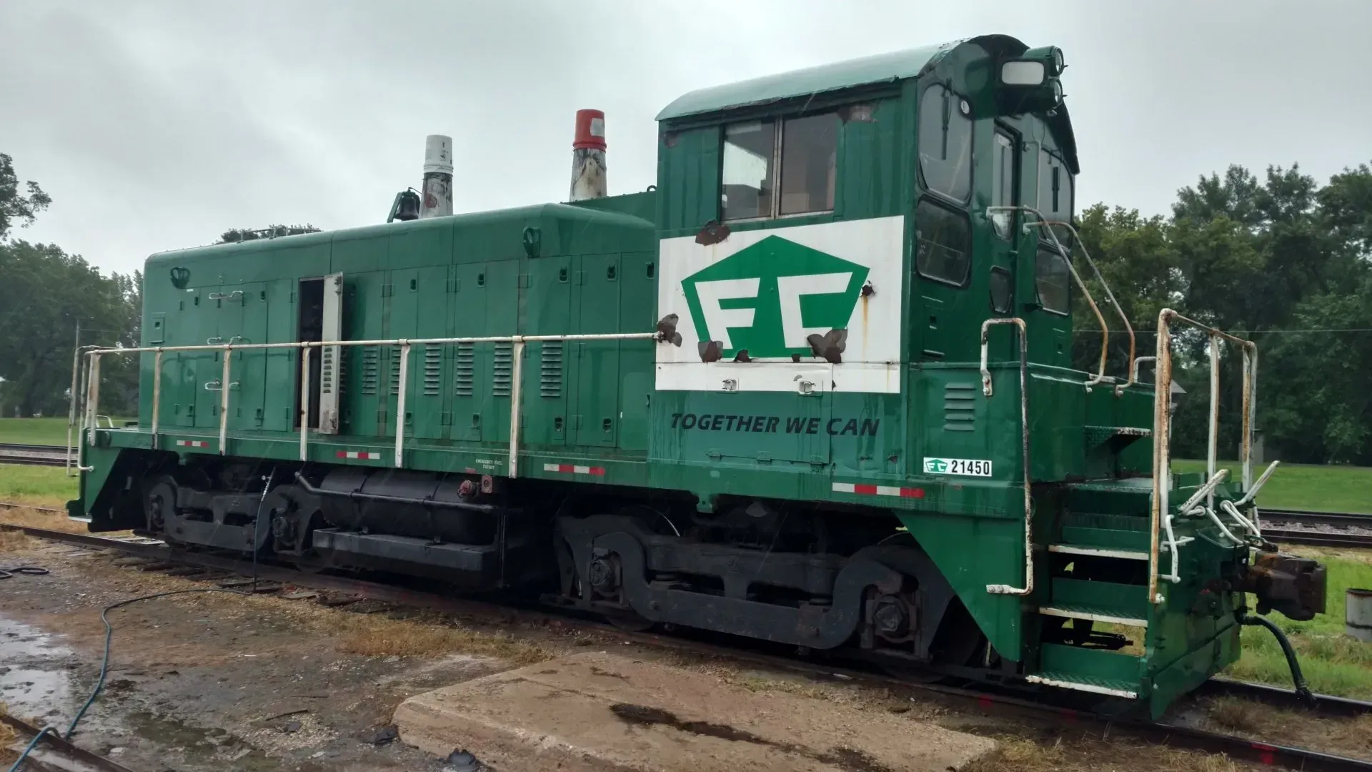 Green diesel locomotive on tracks in a rail yard, marked with large white “FF” lettering.