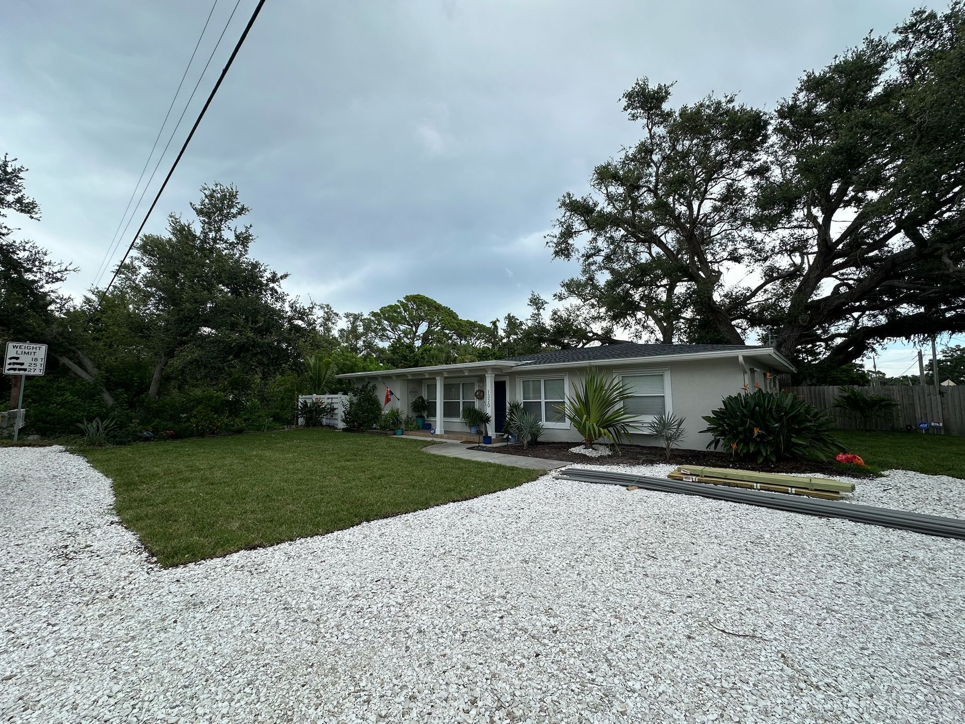 A single-story house with a white exterior, surrounded by green grass and white gravel.