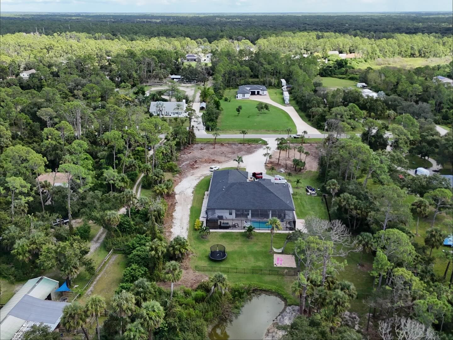 Aerial view of a suburban neighborhood with houses surrounded by trees and a pond.