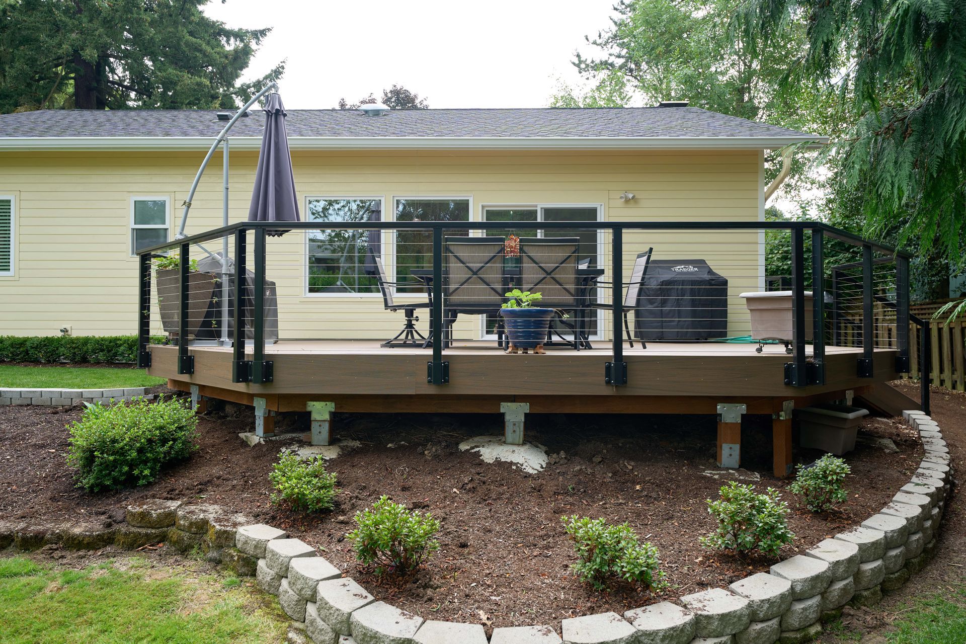 A wooden deck, featuring a railing and a table, providing a cozy outdoor space for relaxation and gatherings.
