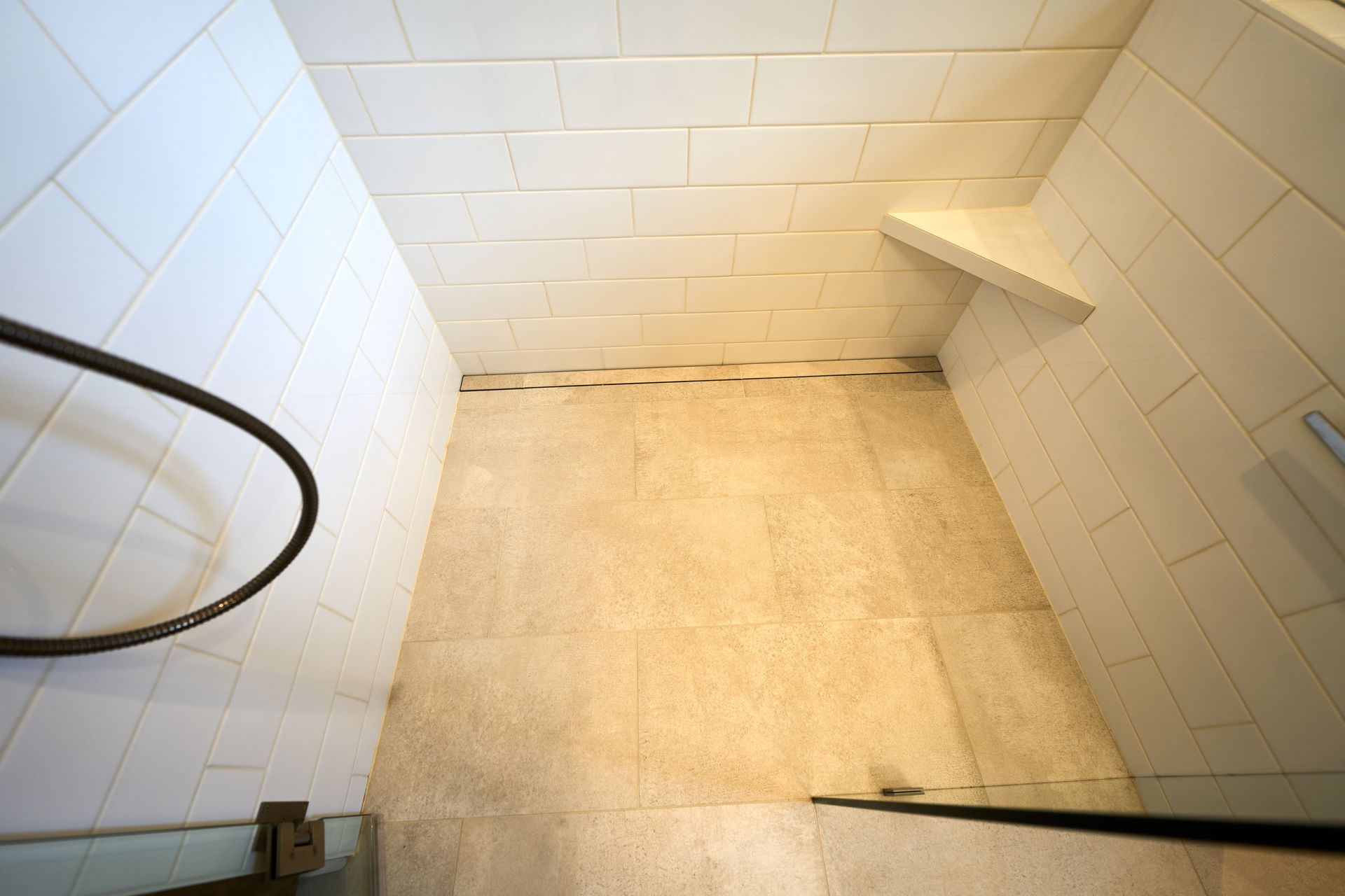 A bathroom with white tiles and a walk in shower.
