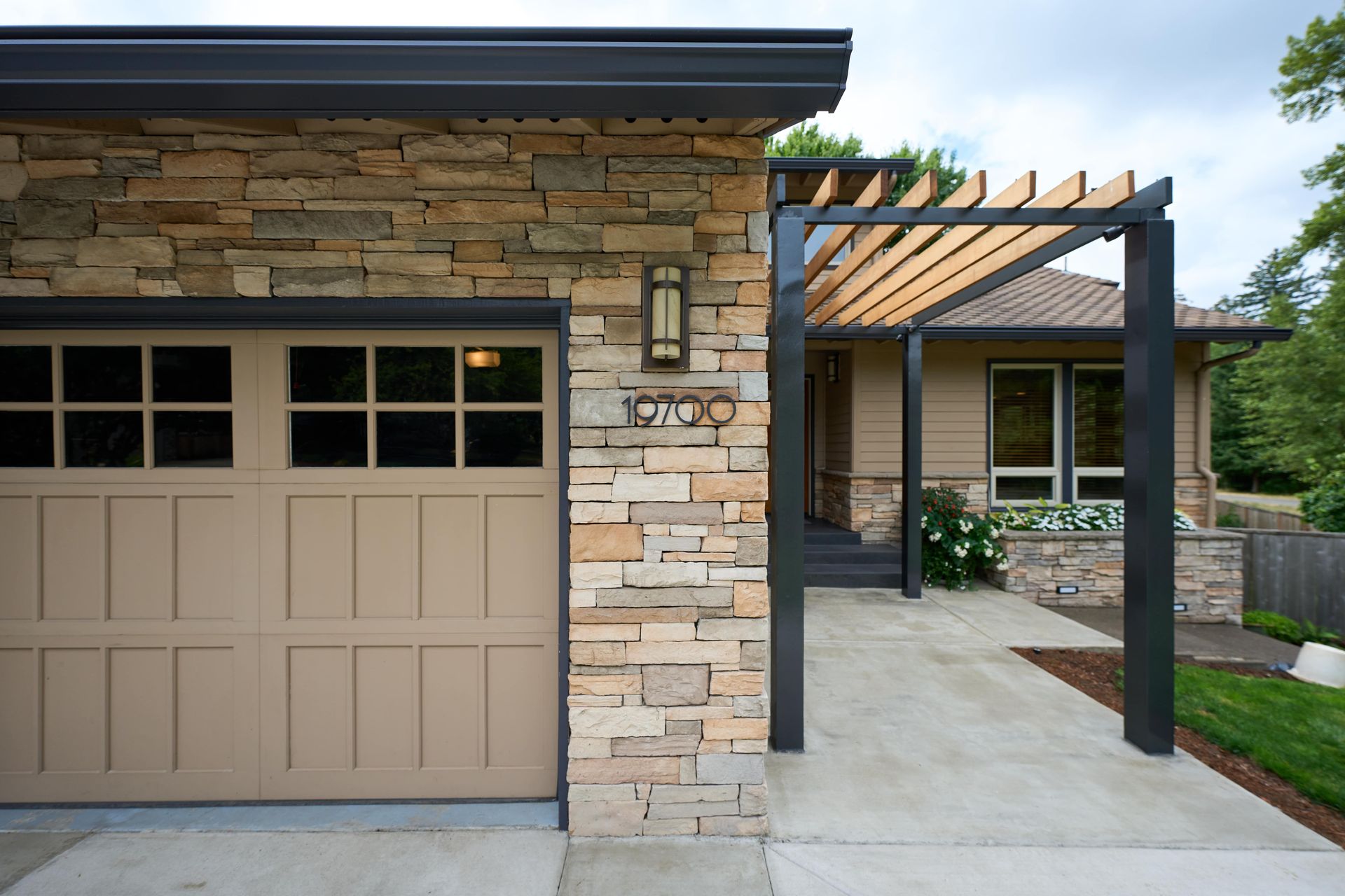 A house with a garage door and a stone wall.