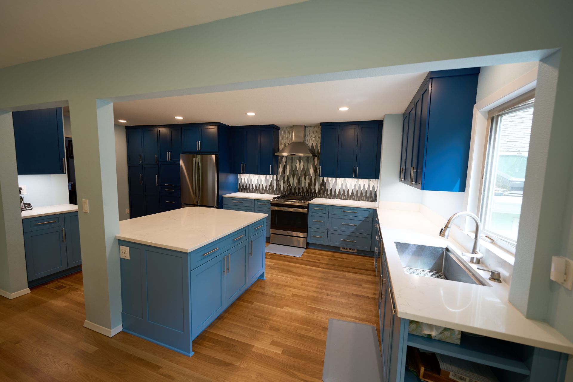 A kitchen with blue cabinets and white counter tops.