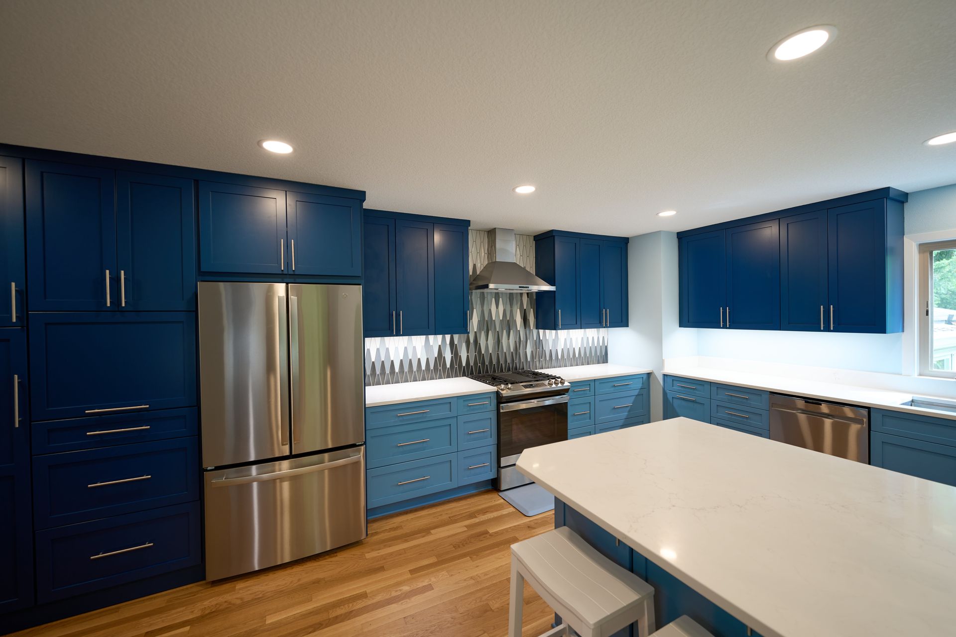 A kitchen with blue cabinets and stainless steel appliances.