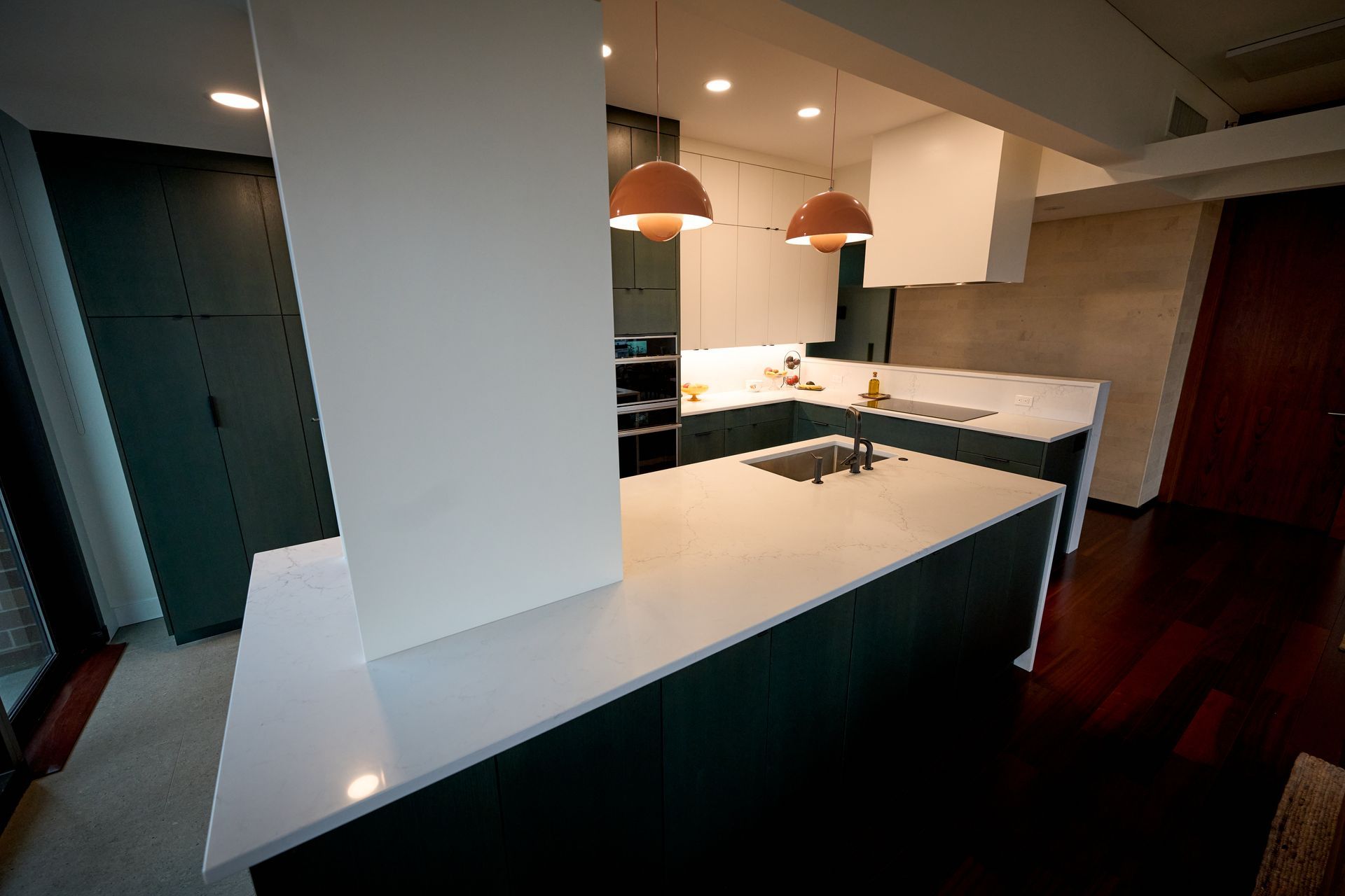 A kitchen with white counter tops and black cabinets.