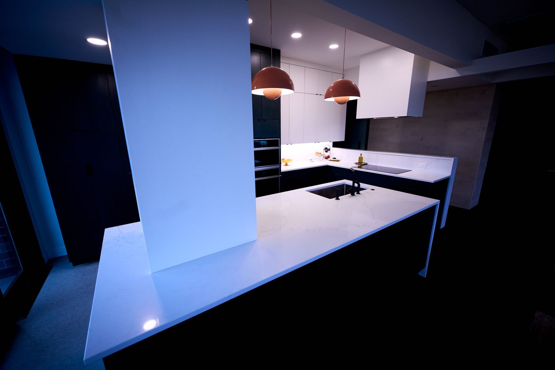 A kitchen with white counter tops and black cabinets.