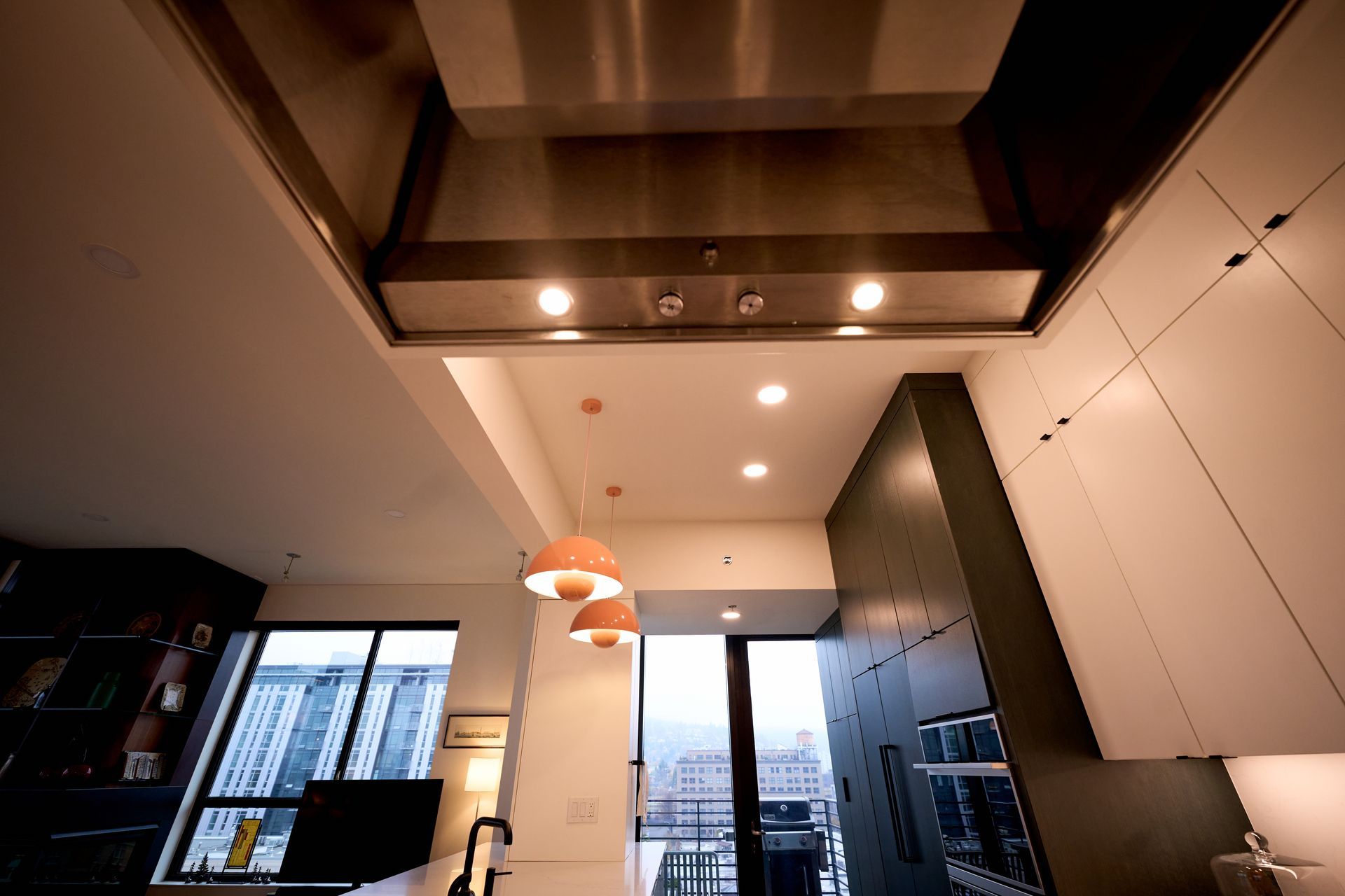 A kitchen with a stainless steel hood hanging from the ceiling.