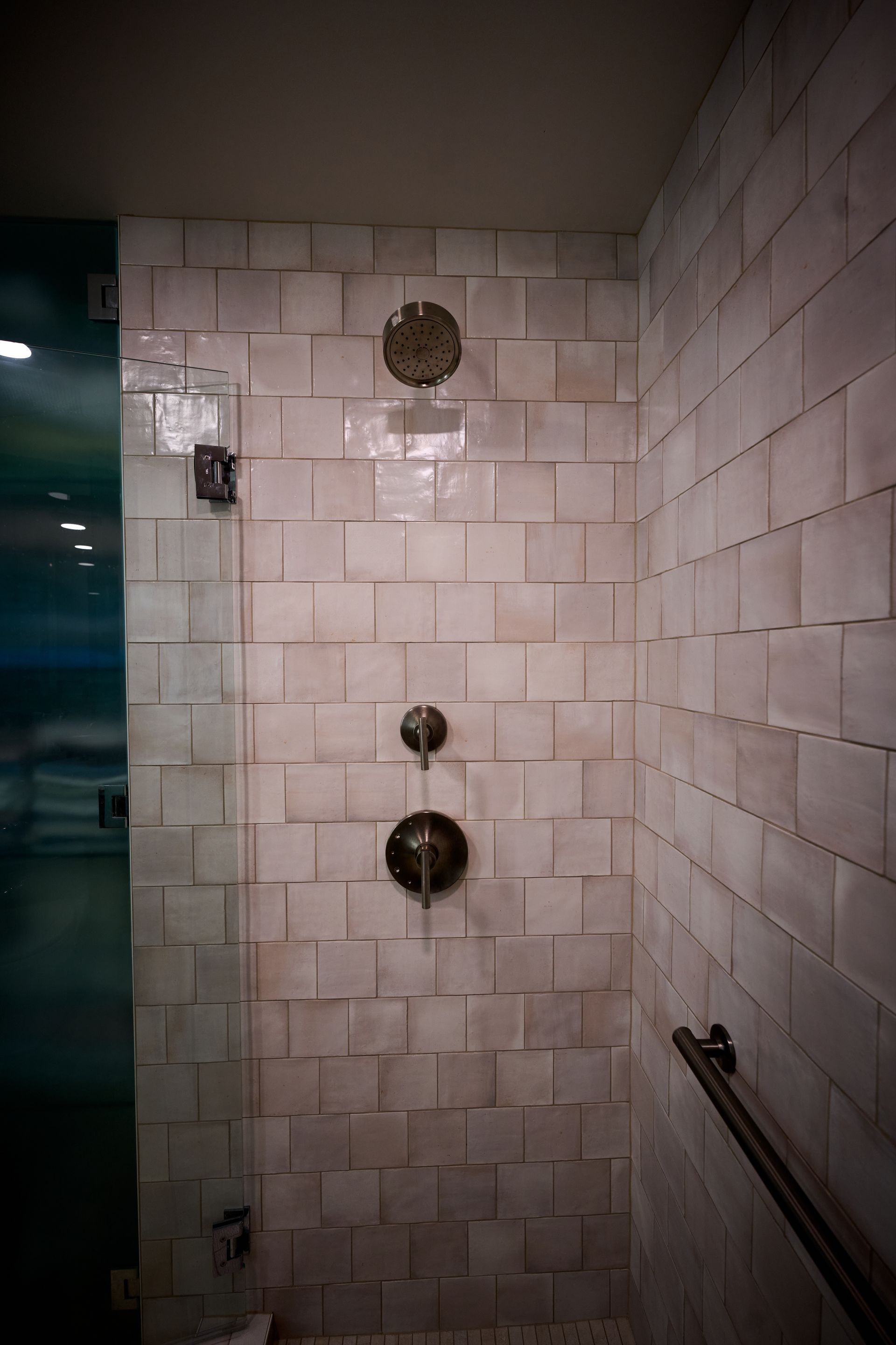 A shower with a glass door and a brick wall.