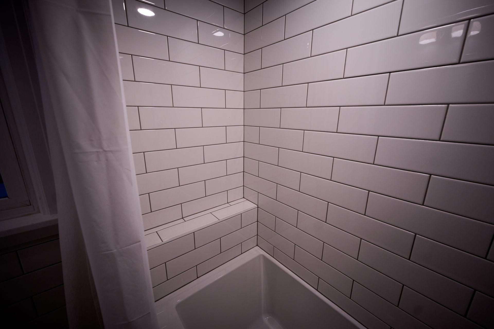 A bathroom with white subway tiles and a bathtub.
