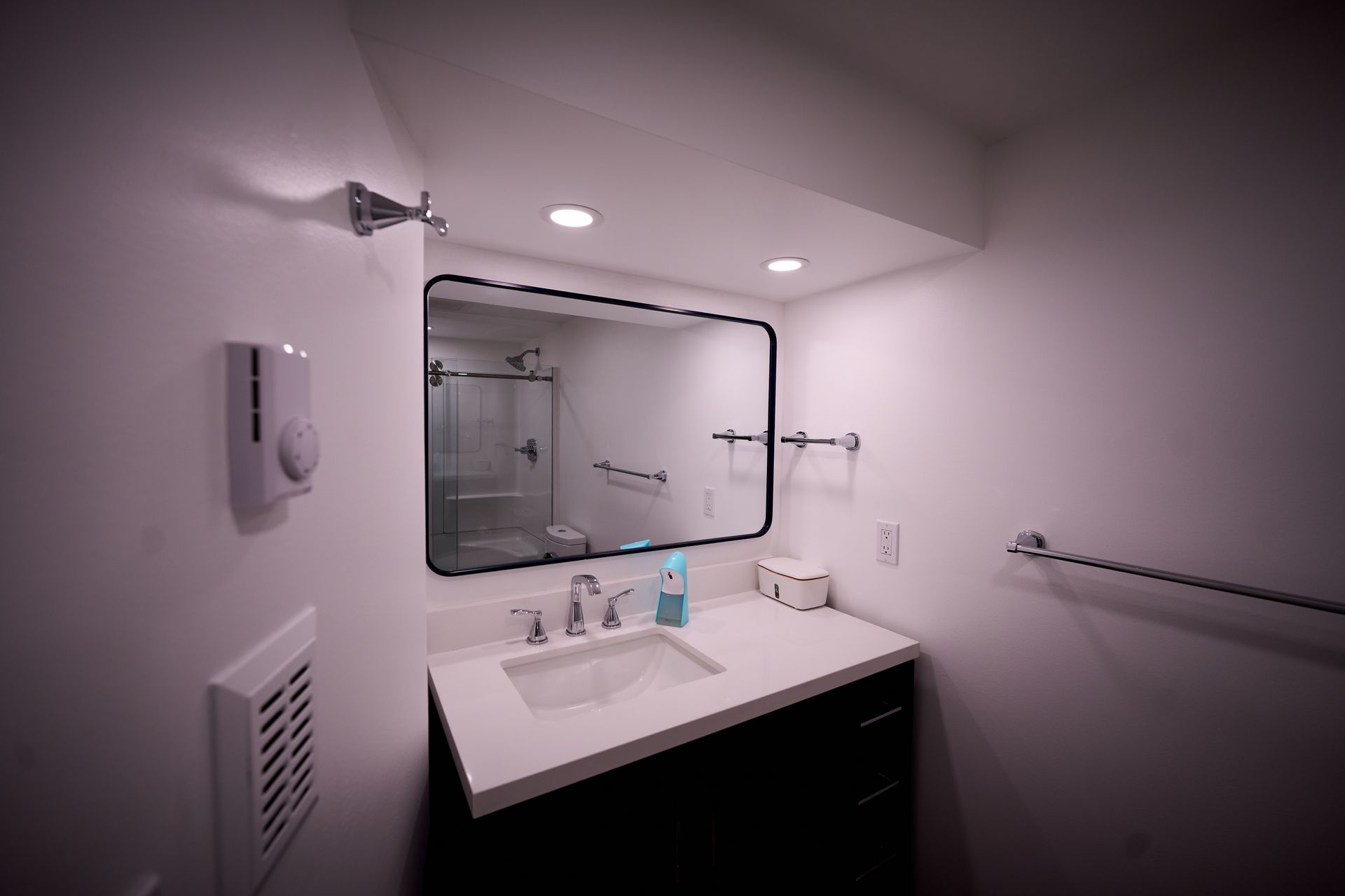 A bathroom with a sink, mirror and shower.