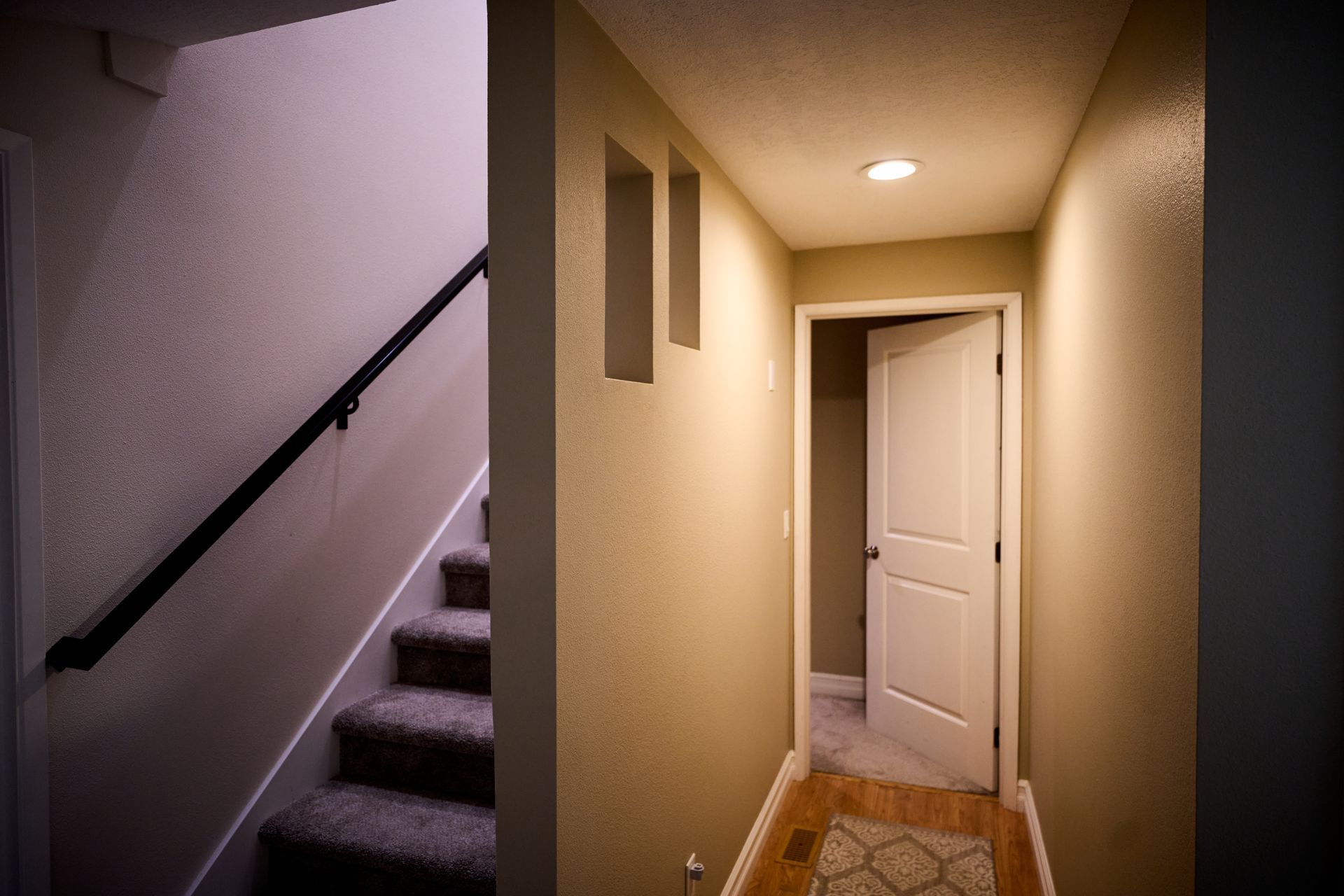 A hallway with stairs and a door in a house.