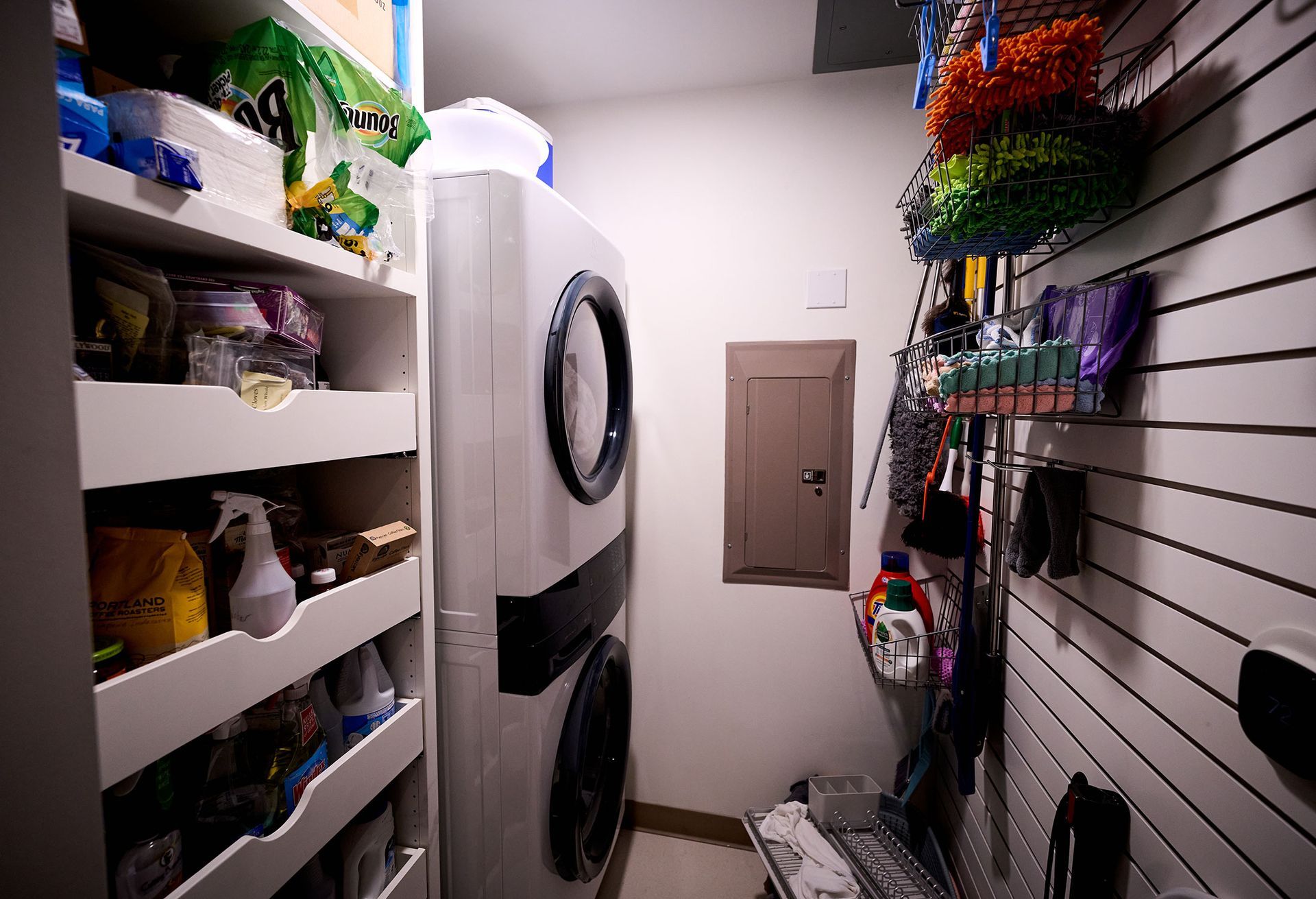 A laundry room with a washer and dryer and lots of shelves.