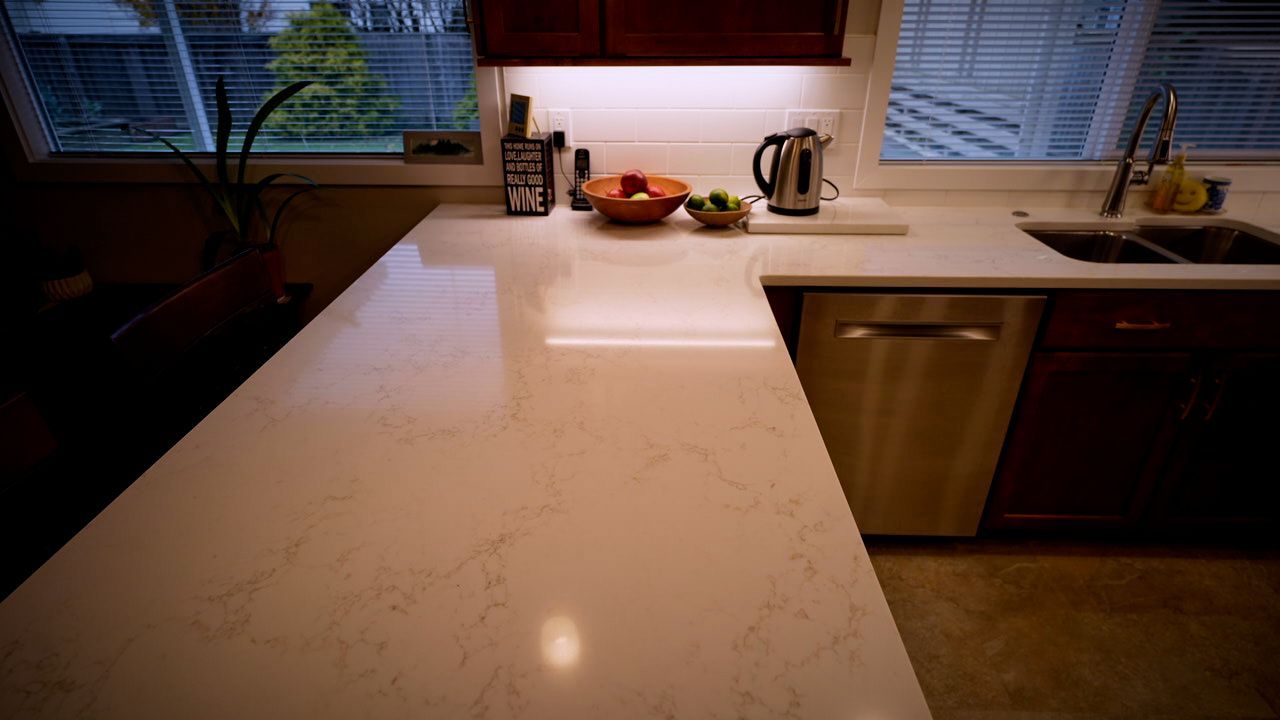A kitchen counter with a bowl of fruit on it and a sink.