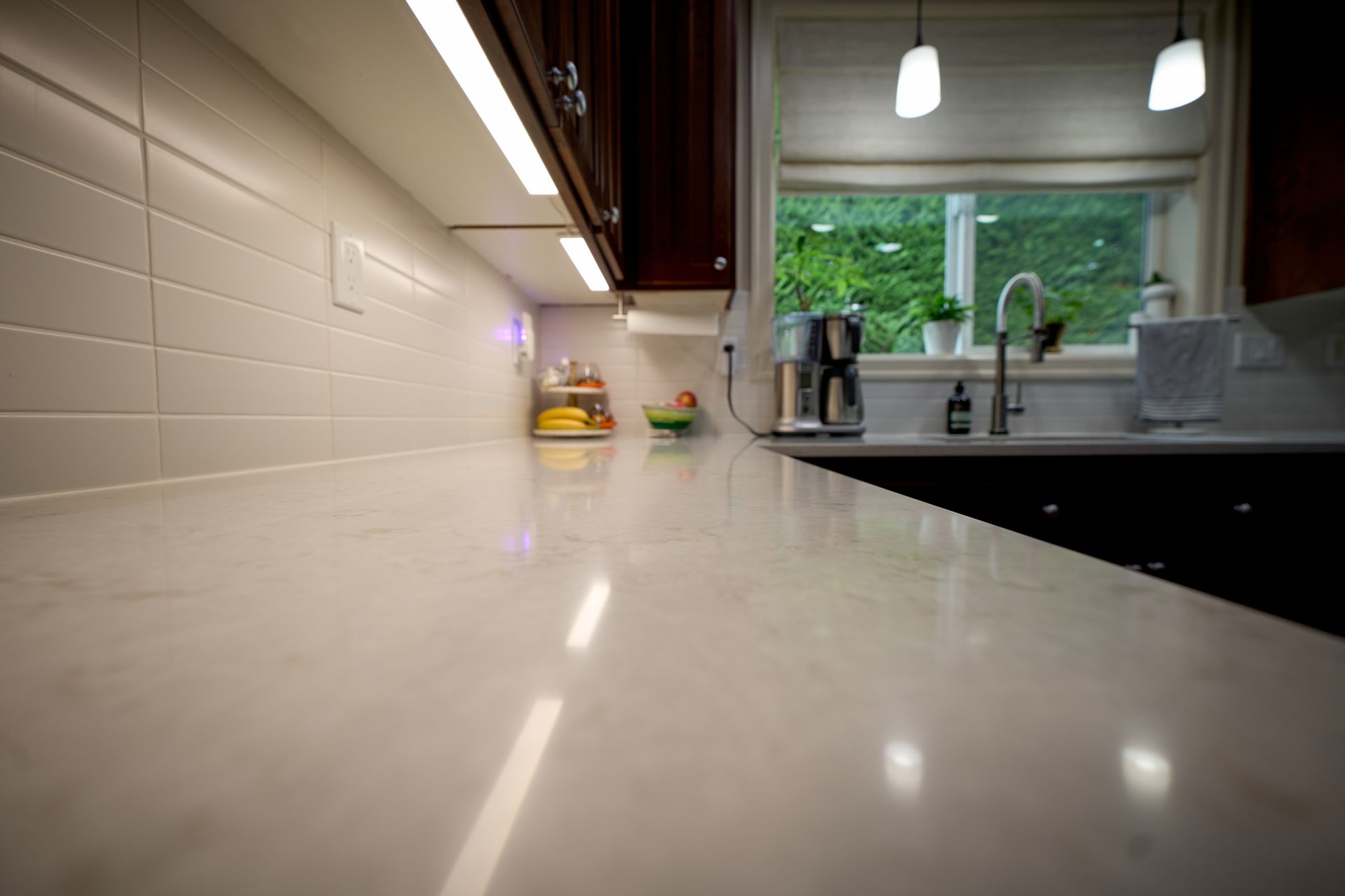 A kitchen counter with a sink and a window in the background.