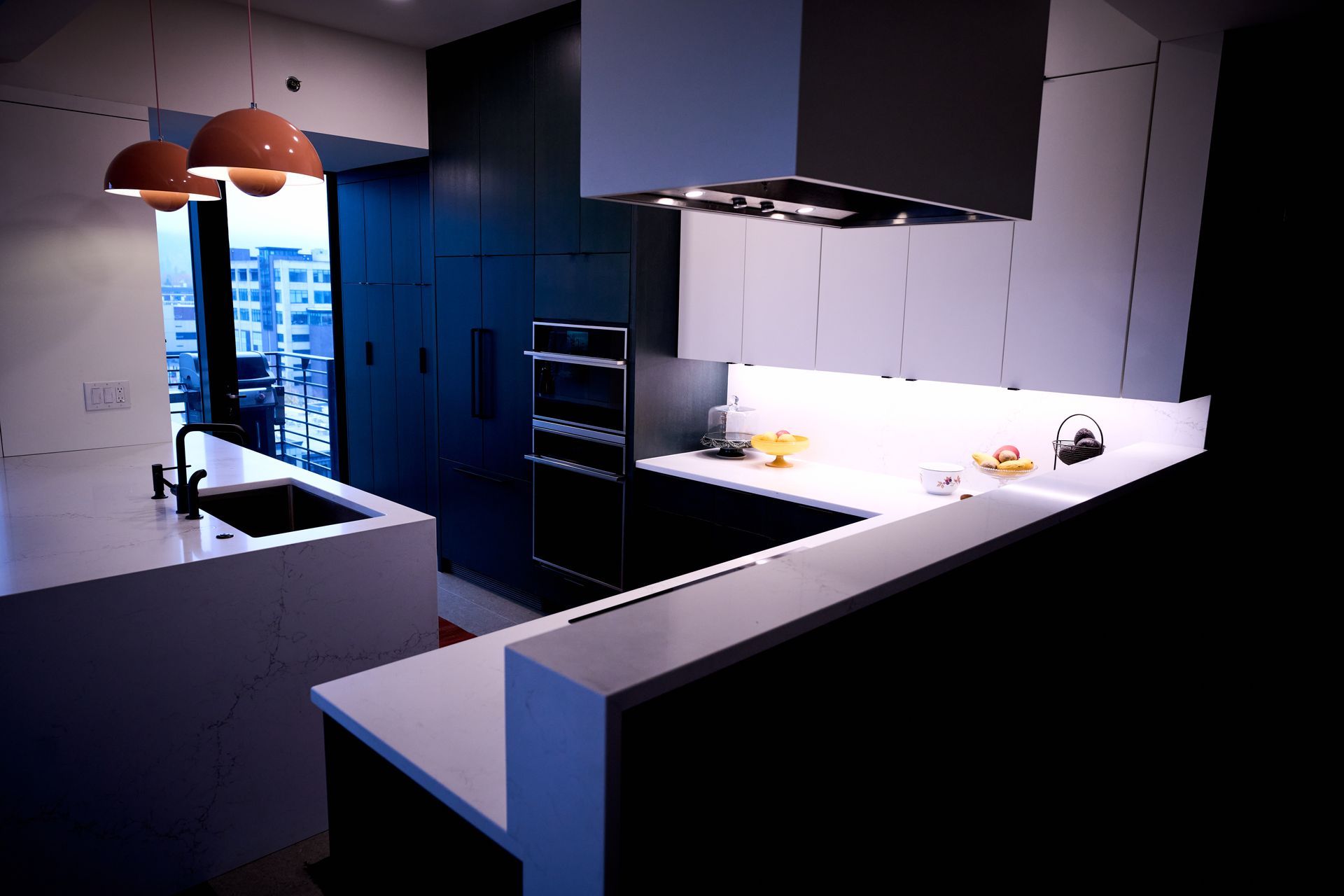 A kitchen with black cabinets and white counter tops.