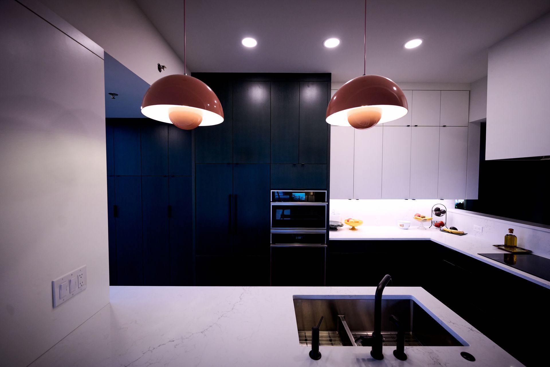 A kitchen with a sink and two lamps hanging from the ceiling.