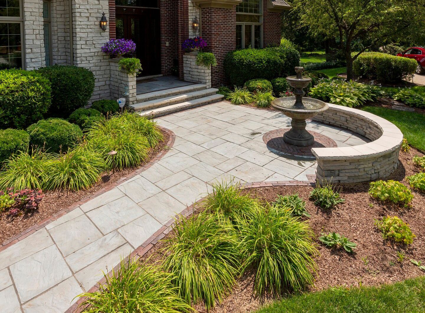 a brick house with a walkway and a fountain in front of it