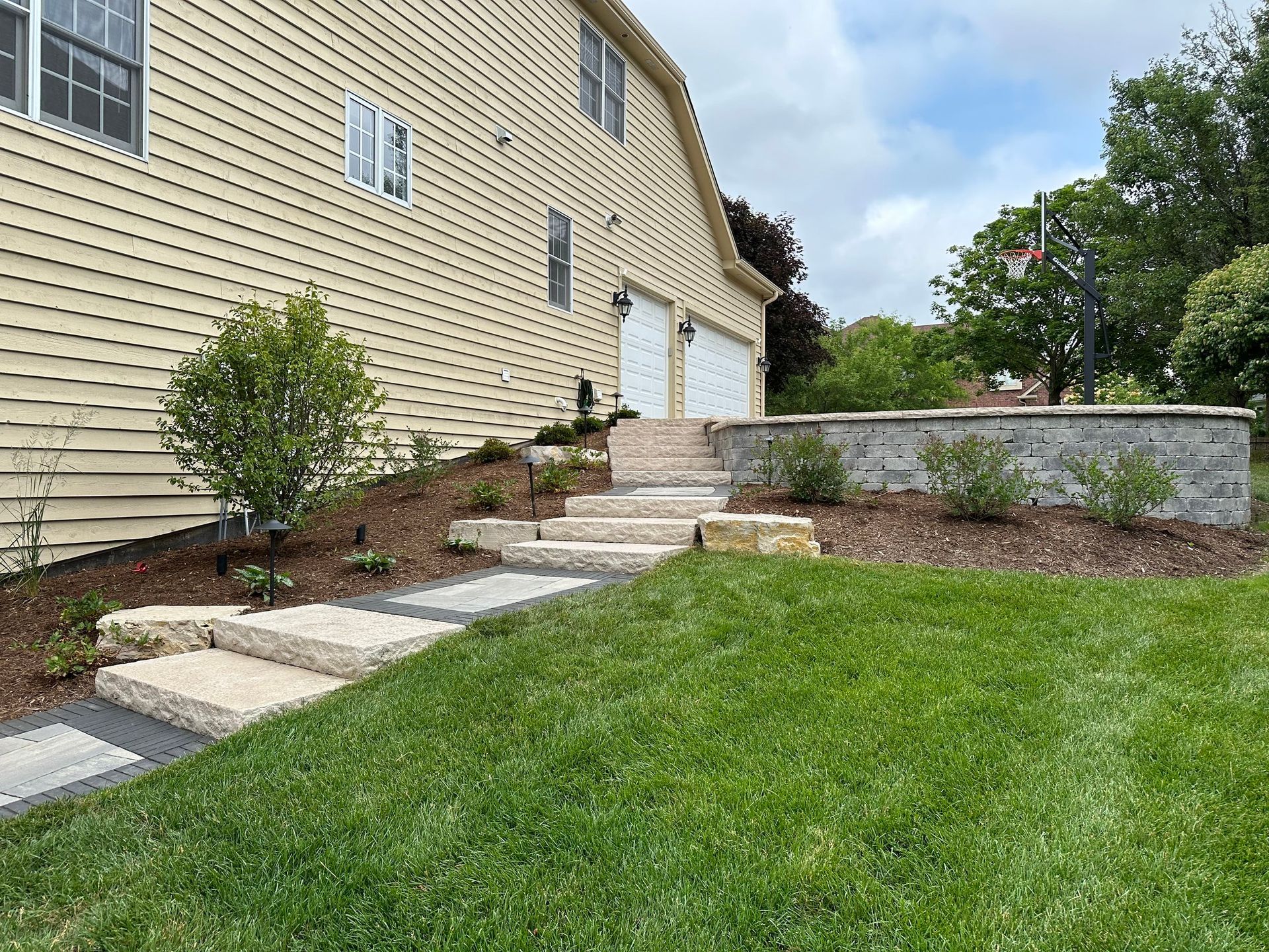 a house with stairs leading up to it and a lush green lawn .