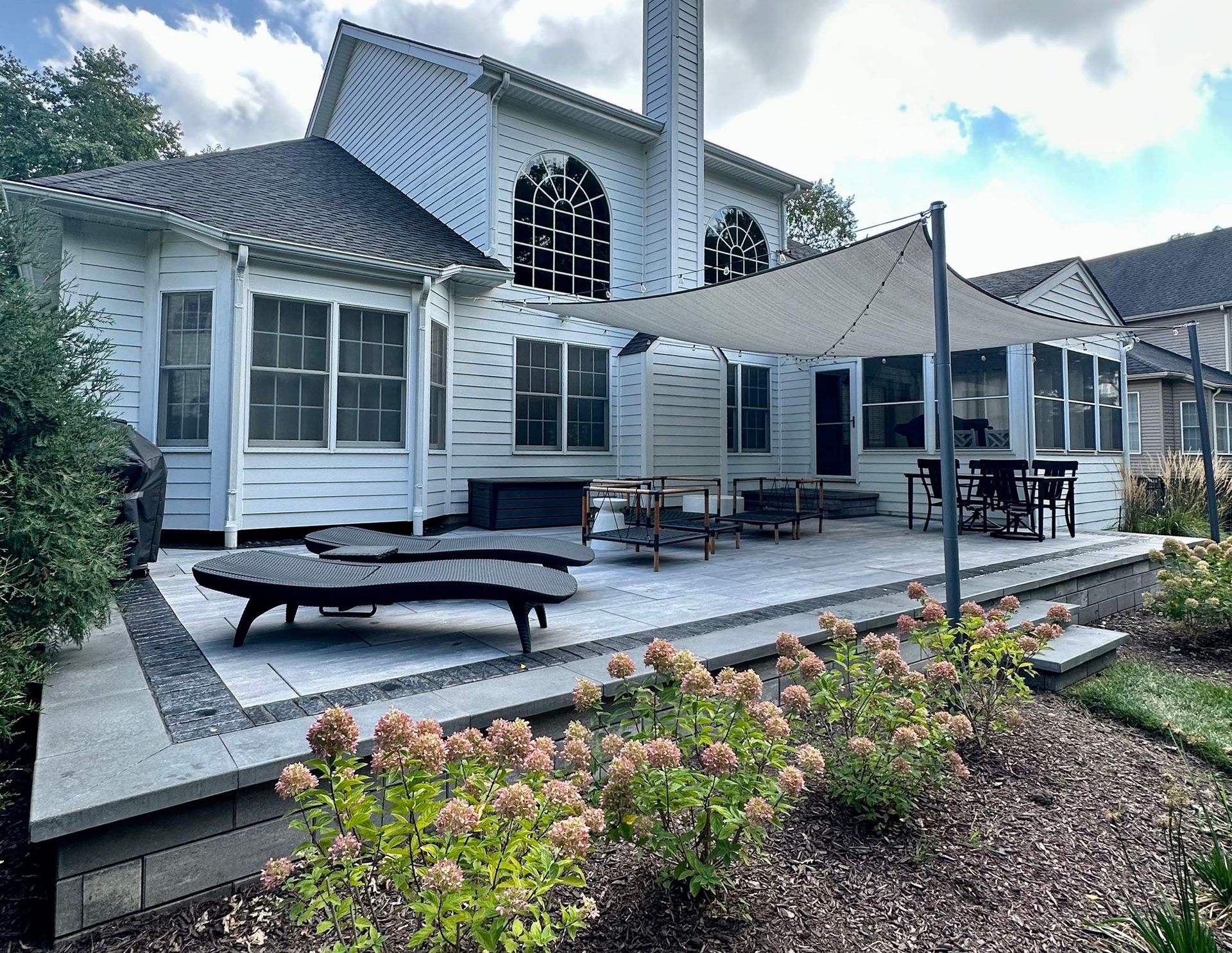 a large white house with a patio and shade in front of it