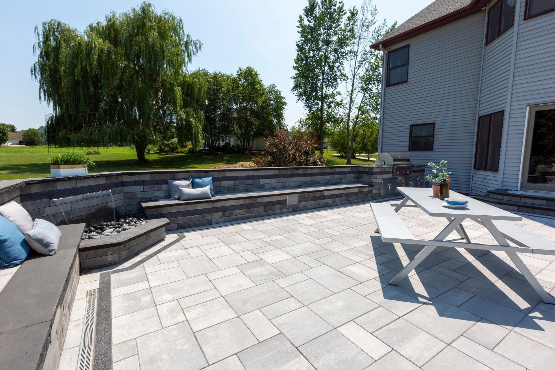 a patio with a picnic table and a fire pit in front of a house