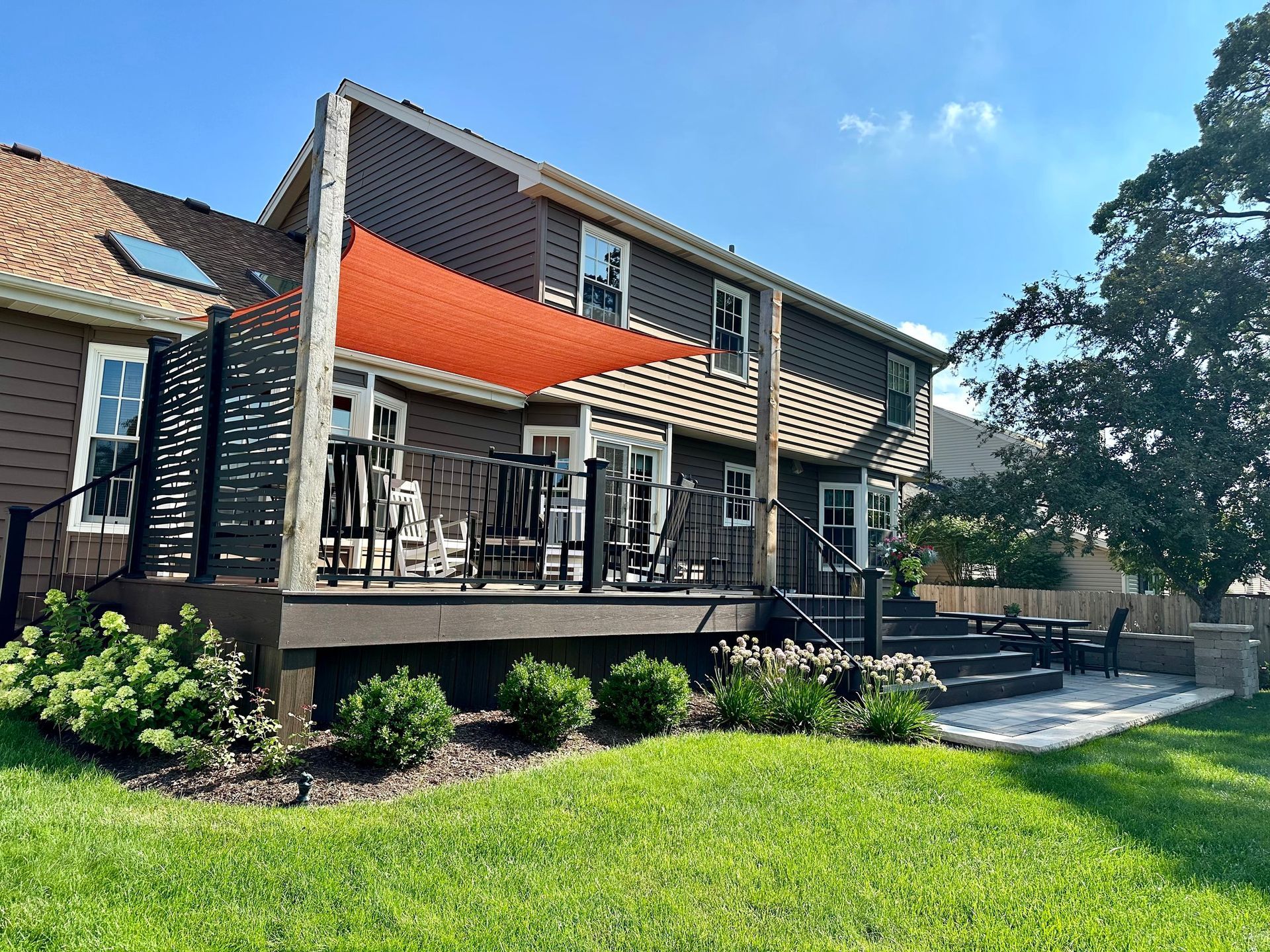a large house with a large deck and a red awning