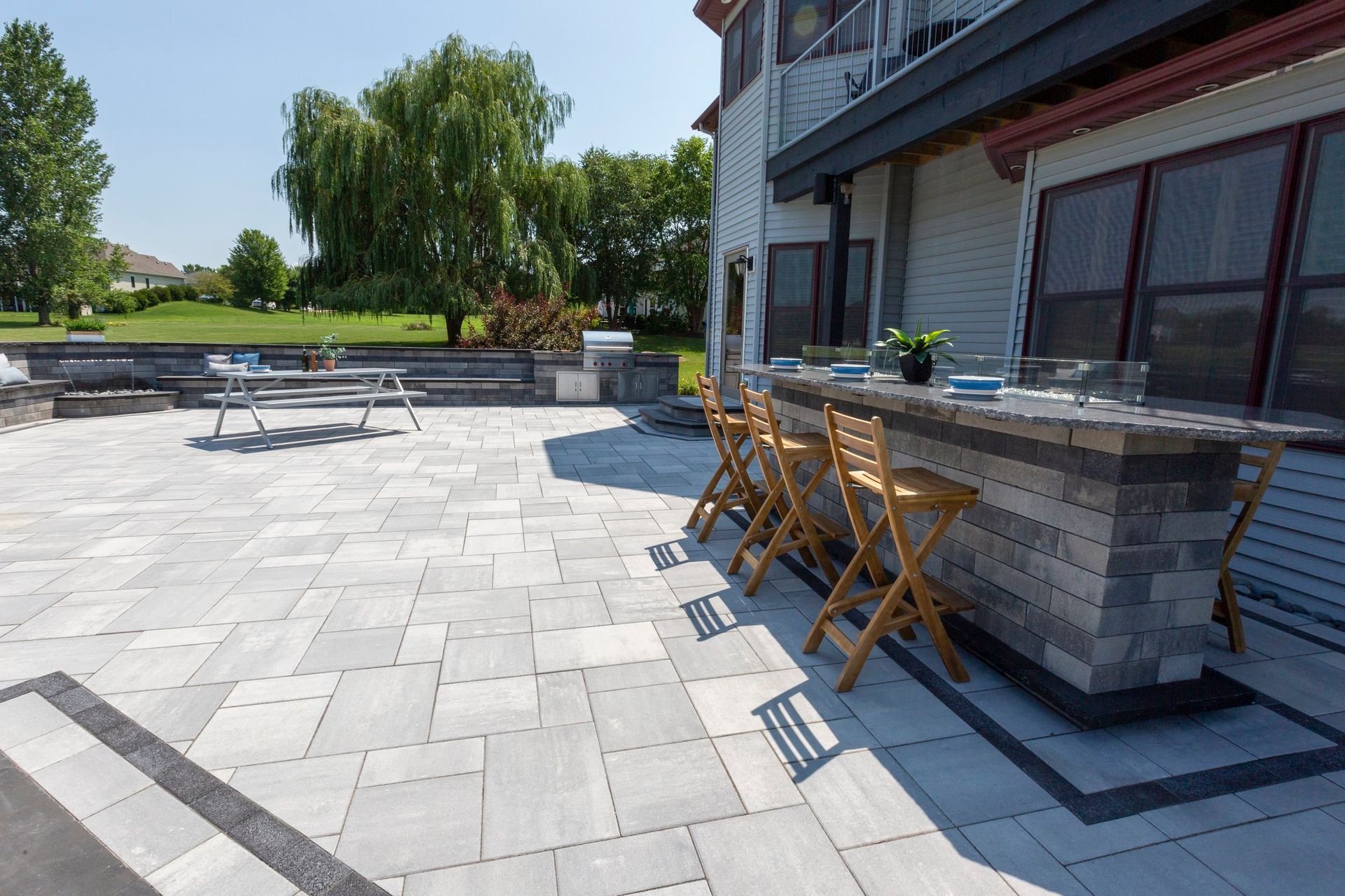 a patio with a bar and chairs in front of a house