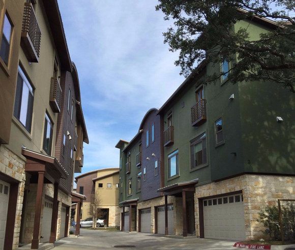A row of apartment buildings are lined up on a street