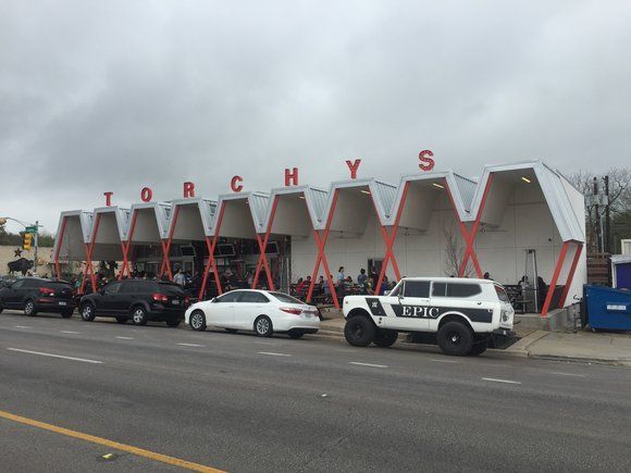 A row of cars are parked in front of a building that says torchys.