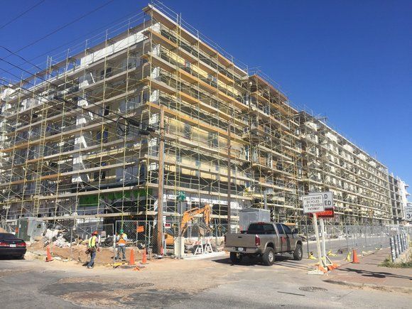 A large building under construction with scaffolding around it and a truck parked in front of it.