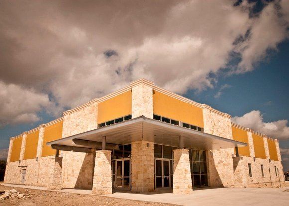 A large yellow building with a cloudy sky in the background