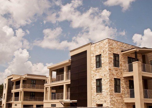 A row of apartment buildings against a blue sky with clouds
