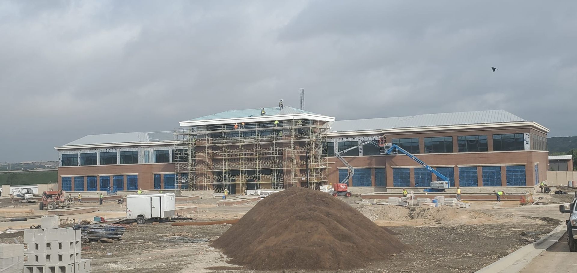 A large building under construction with a pile of dirt in front of it