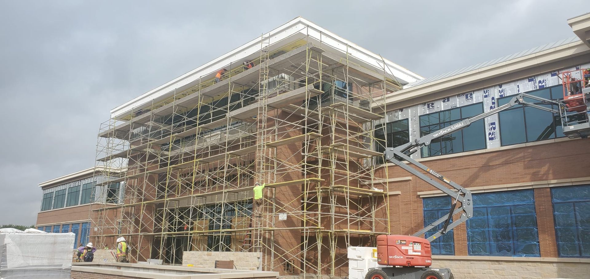 A large brick building is being built with scaffolding around it
