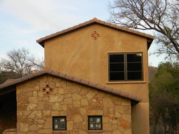 A stone building with a tiled roof and two windows