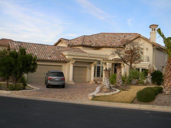 A car is parked in front of a large house