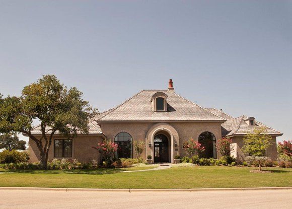 A large house is sitting on top of a lush green lawn.