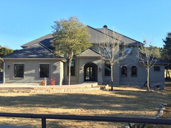 A large house with a slate roof and trees in front of it.