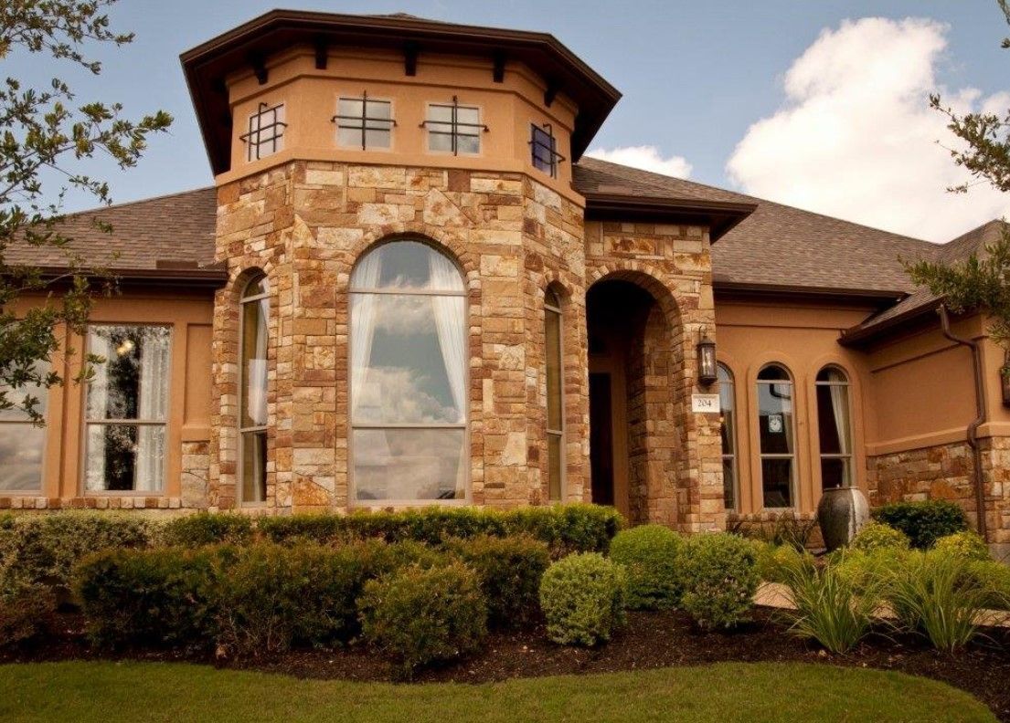 A large house with a lot of windows and bushes in front of it