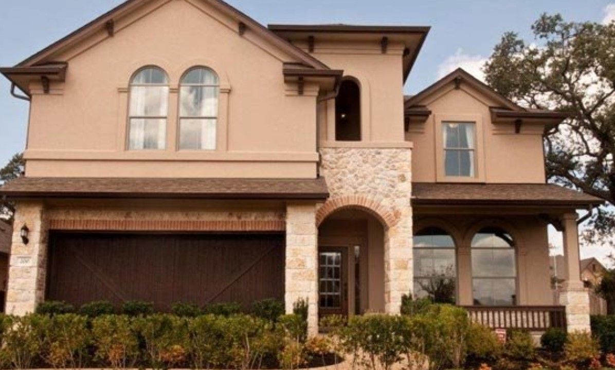 A large house with arched windows and a brown garage door