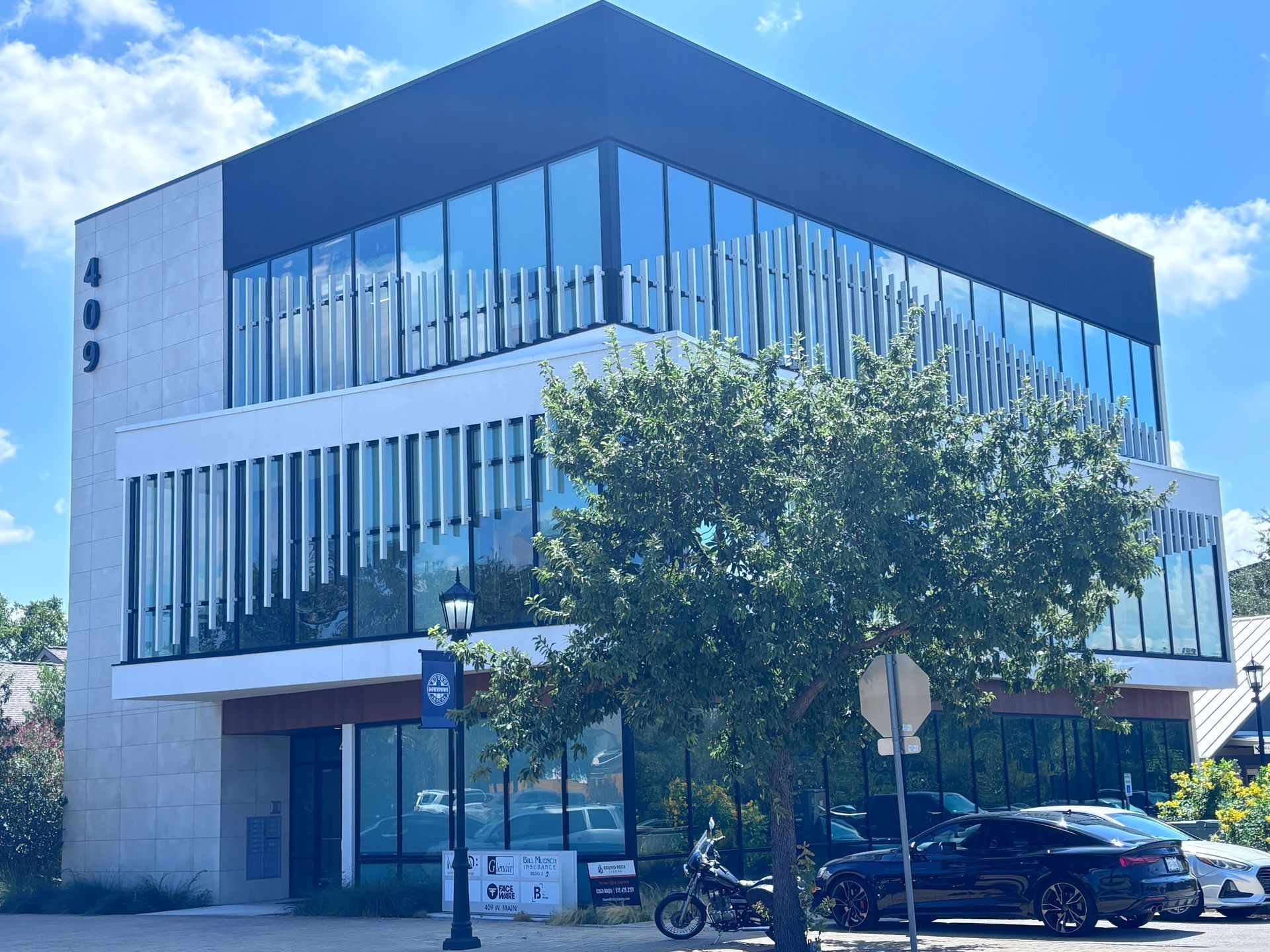 Modern three-story building with glass windows, white and black exterior.