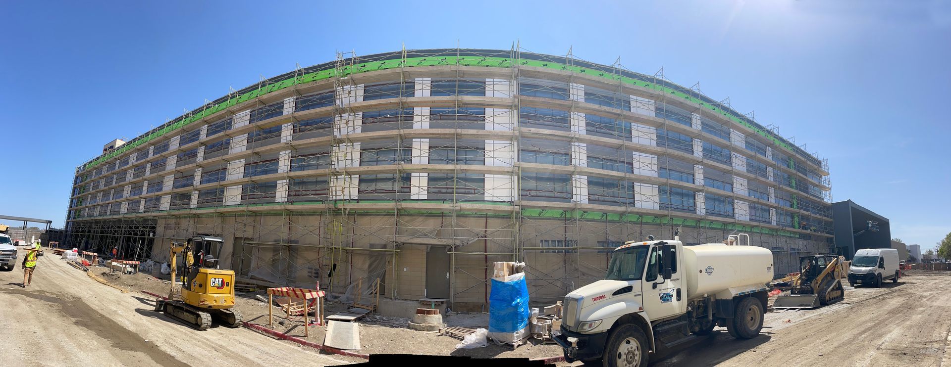 A large building under construction with a tanker truck parked in front of it.